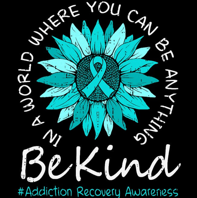 A teal and blue sunflower with a teal ribbon in the center, surrounded by the text 'IN A WORLD WHERE YOU CAN BE ANYTHING Be Kind' and '#Addiction Recovery Awareness' in white and teal lettering on a black background.